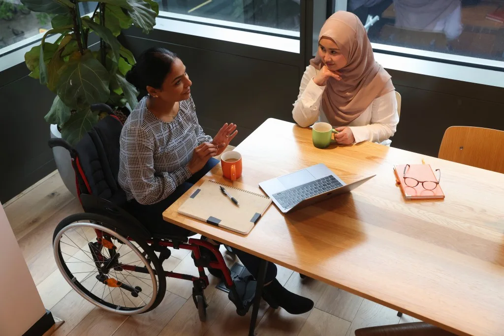 Support worker talking with disabled woman in wheelchair at table