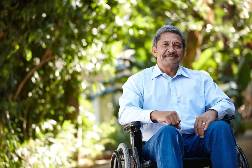 Disabled man in wheelchair outside smiling at camera