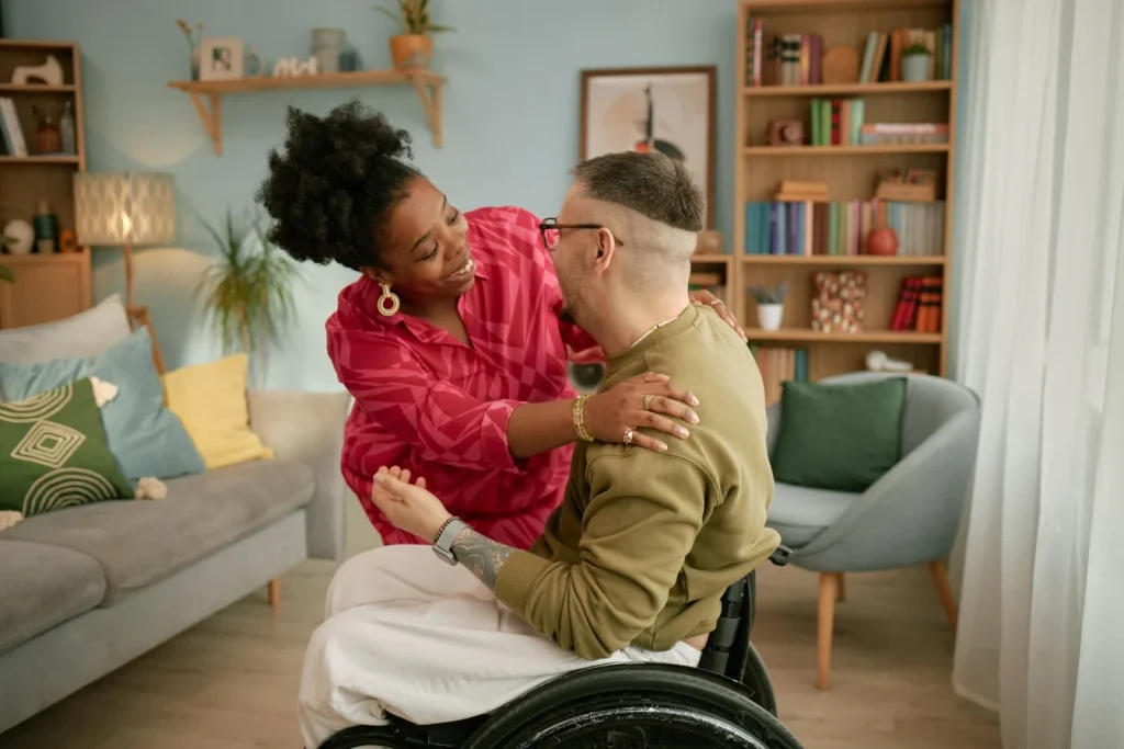 Support worker hugging disabled man in wheelchair